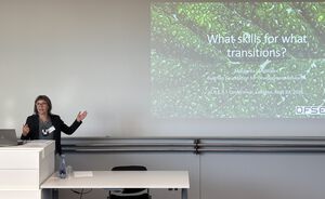Eine Frau spricht an einem Podium, neben ihr ist eine Powerpoint Präsentation. Eine Frau spricht an einem Podium, neben ihr ist eine Powerpoint Präsentation.