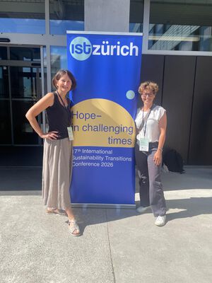 Zwei Frauen stehen an beiden Seiten eines blauen Plakats mit der Aufschrift: IST Konferenz. Zwei Frauen stehen an beiden Seiten eines blauen Plakats mit der Aufschrift: IST Konferenz.