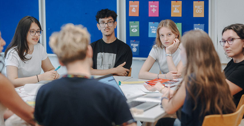 Jugendliche arbeiten miteinander um einen Tisch sitzend