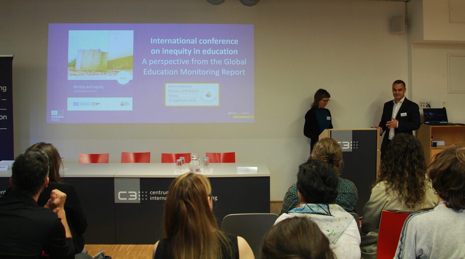 Zwei Personen stehen vorne an einem Podium neben einer Powerpoint-Präsentation. Zwei Personen stehen vorne an einem Podium neben einer Powerpoint-Präsentation.