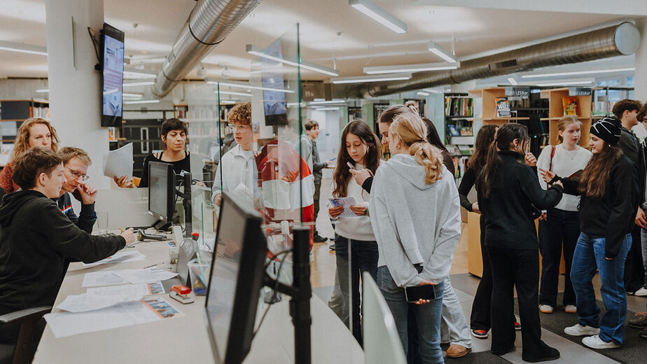 Schüler*innen stehen beim Desk der C3-Bibliothek zum Checkin an