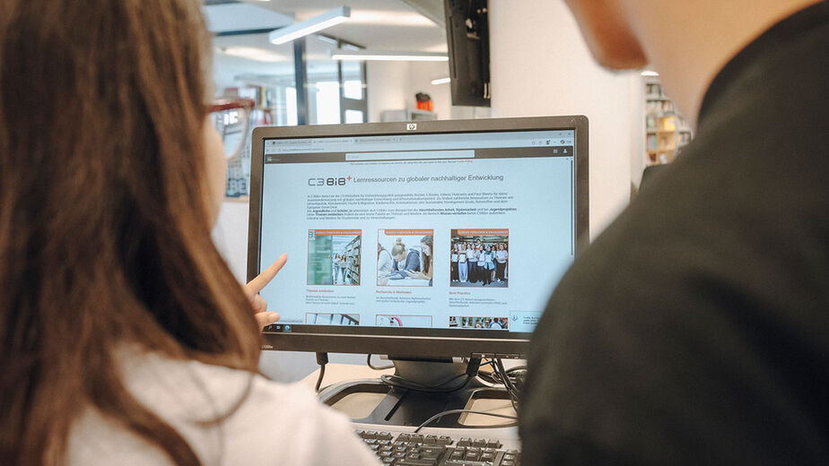 2 Personen schauen auf einen Bildschirm